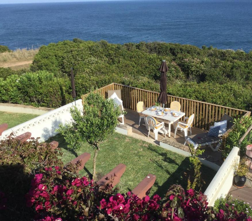 un giardino con tavolo, sedie e l'oceano di Casa Rosa Azul - Terracos de Benagil (Cliffside) a Benagil