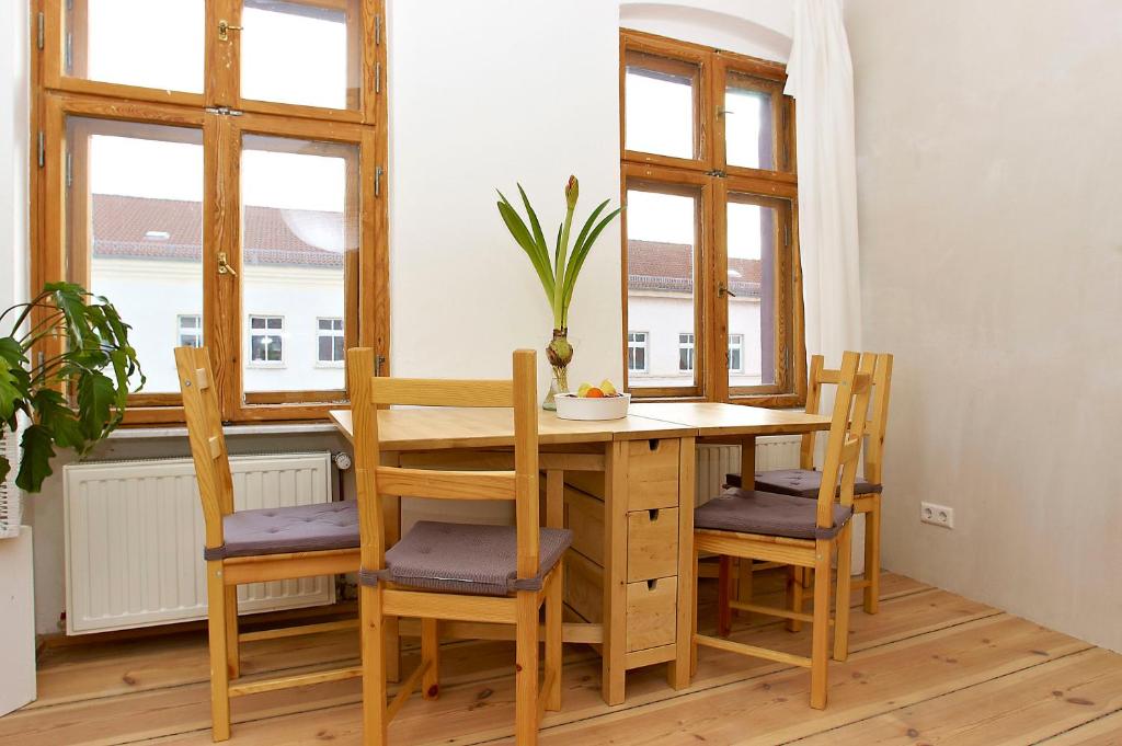 Berlin Apartments Mitte في برلين: طاولة وكراسي في غرفة بها نوافذ
