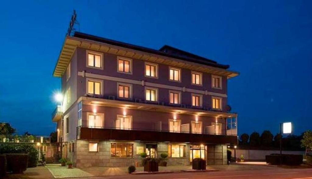 a large building with lit up windows at night at Hotel San Francesco in Borgomanero