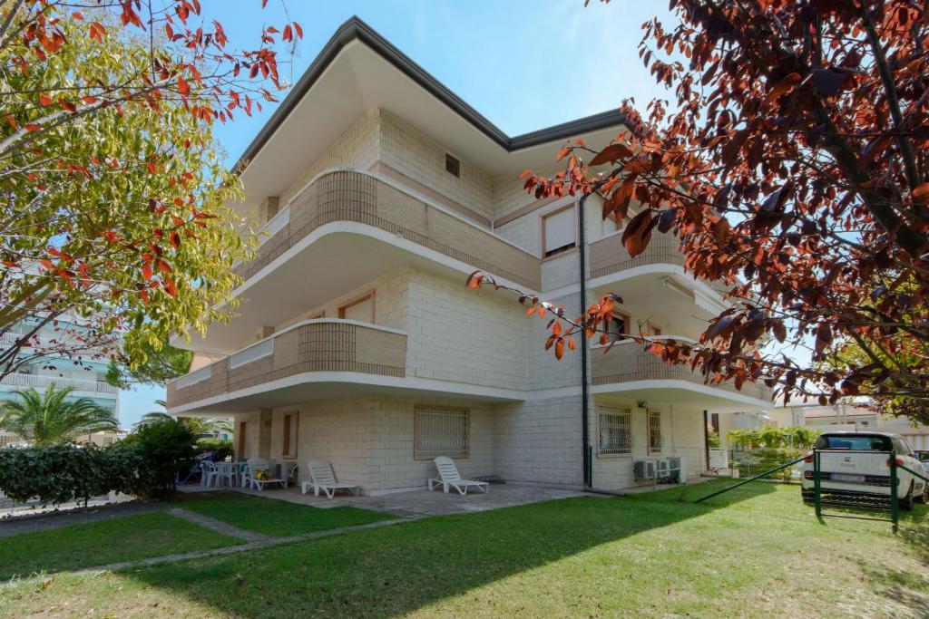 een groot wit gebouw met een gazon ervoor bij Appartamenti Lignano Sabbiadoro - Villa Ammiraglia in Lignano Sabbiadoro