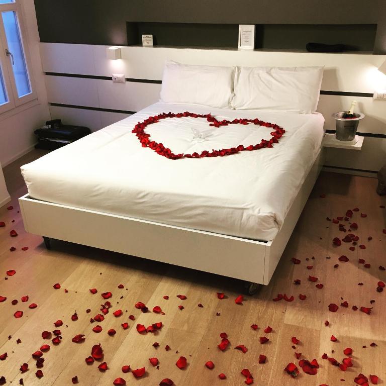 a bed with a heart made out of roses on the floor at Como Luxury Rooms in Como