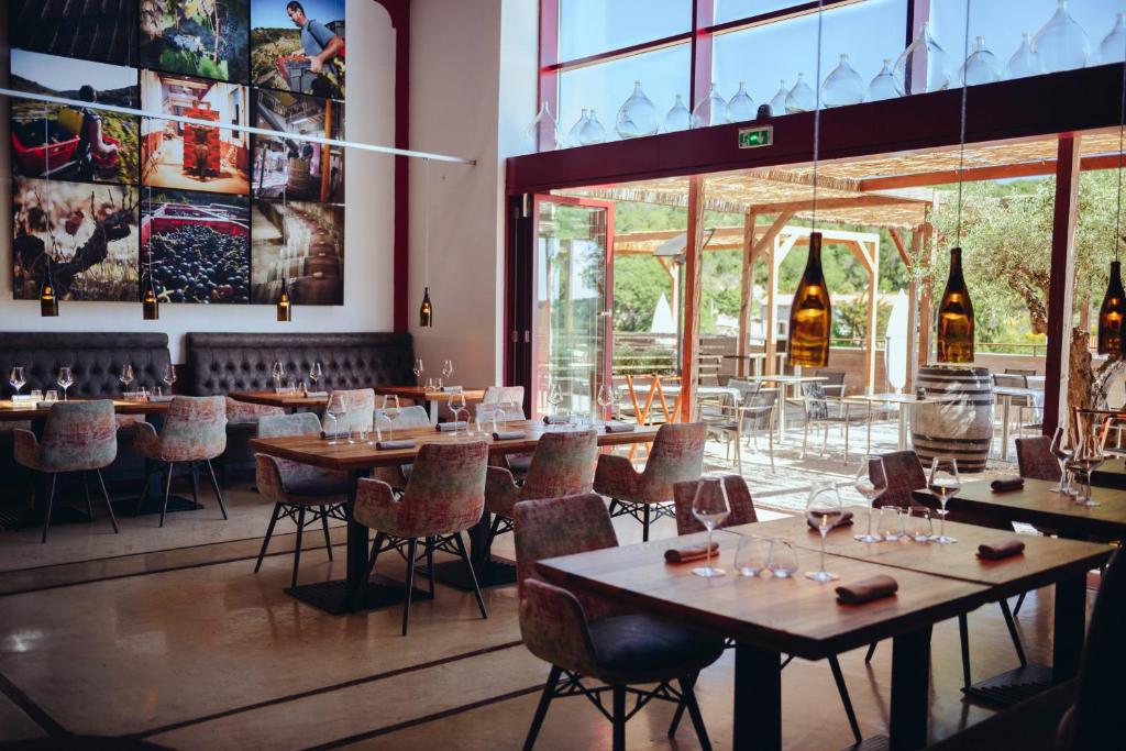 a restaurant with tables and chairs and a large window at Domaine Riberach in Bélesta