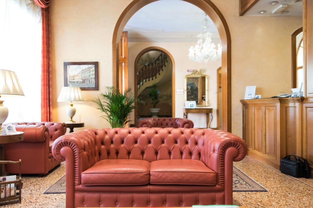 a leather couch in a living room with a mirror at Phi Hotel Dei Medaglioni in Correggio