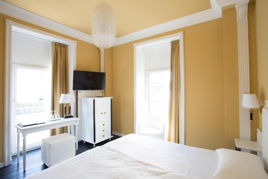 a bedroom with a bed and a desk and window at Greif Hotel Maria Theresia in Trieste