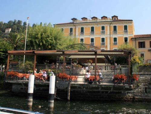 grupa ludzi siedzących w restauracji na wodzie w obiekcie Hotel Excelsior Splendide w mieście Bellagio