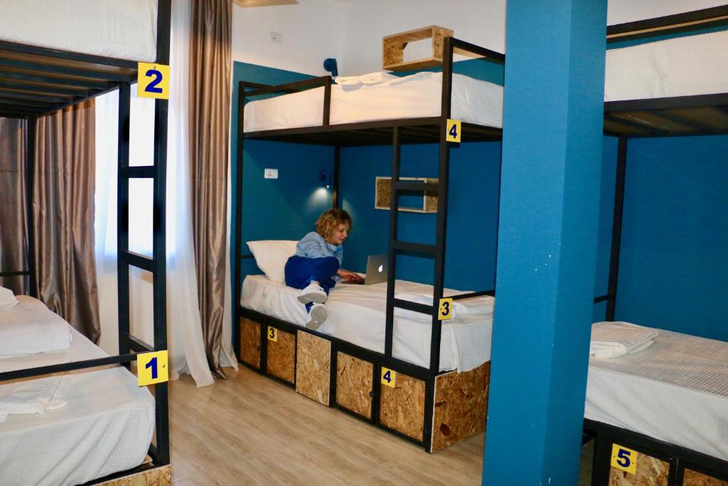 提比里斯的住宿－City Dorm，儿童坐在双层床上,并使用笔记本电脑