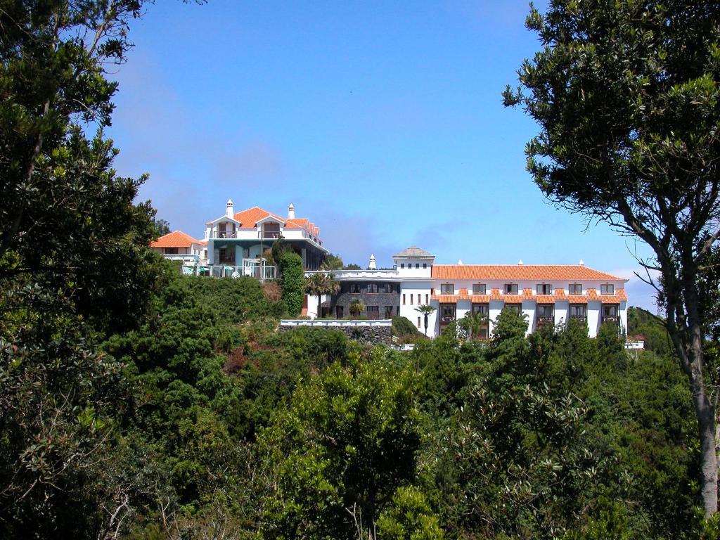 une grande maison au sommet d'une colline avec des arbres dans l'établissement Hotel La Palma Romántica, à Barlovento