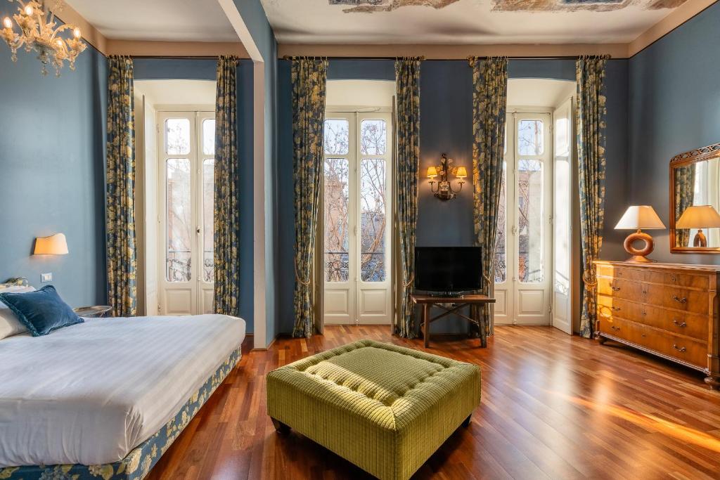 a bedroom with blue walls and a bed and a ottoman at Bellezza Suites in Cagliari