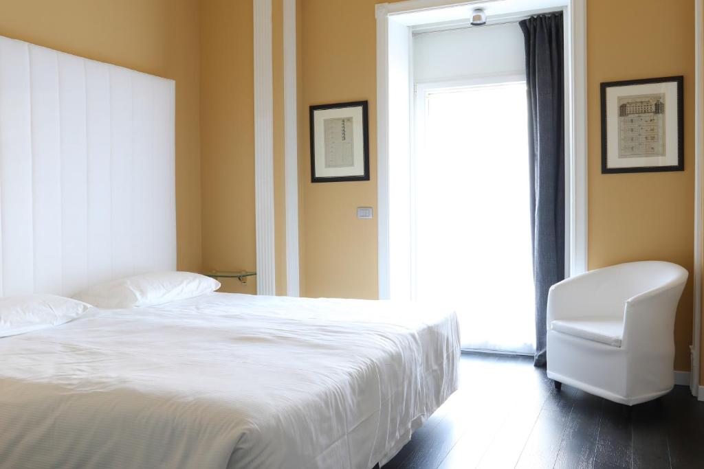 a bedroom with a white bed and a white chair at Greif Hotel Maria Theresia in Trieste
