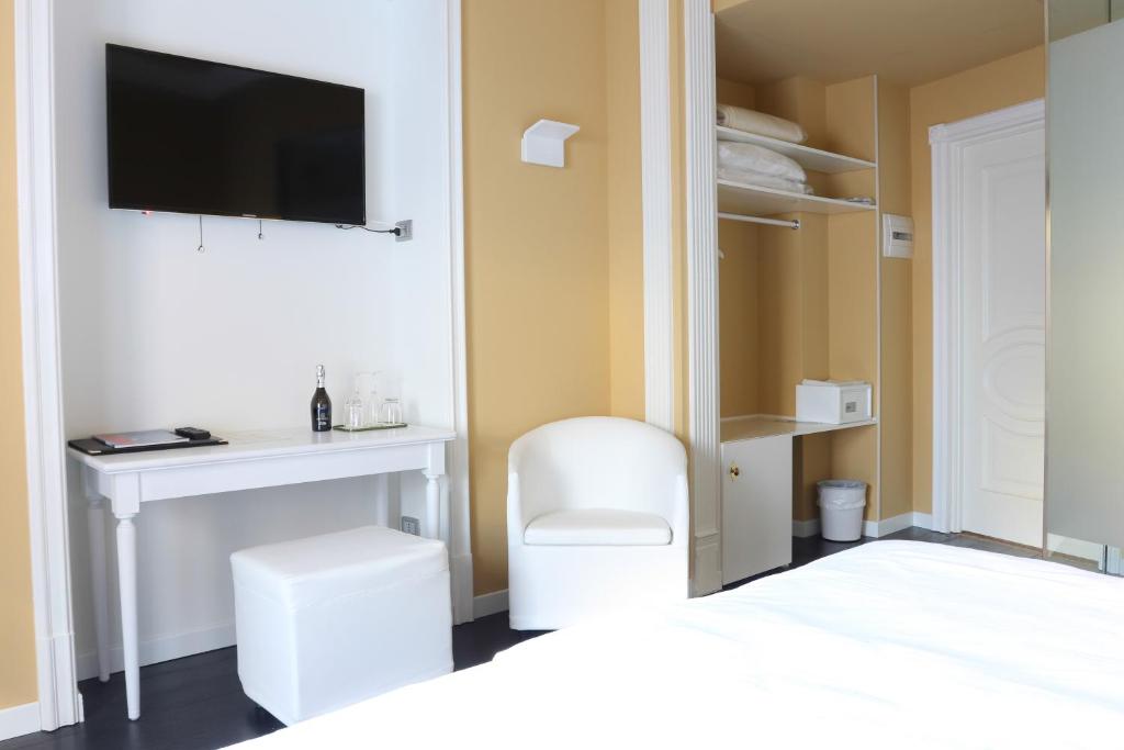 a bedroom with a desk and a tv on a wall at Greif Hotel Maria Theresia in Trieste