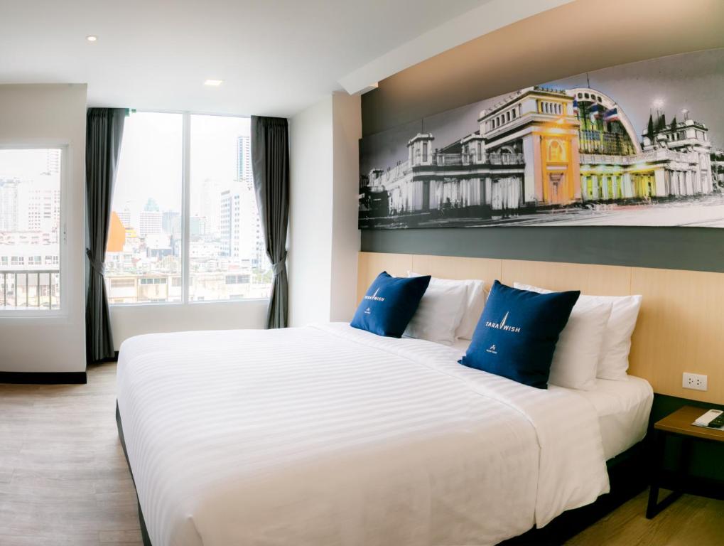 a bedroom with a large white bed with blue pillows at Tarawish Hotel in Bangkok