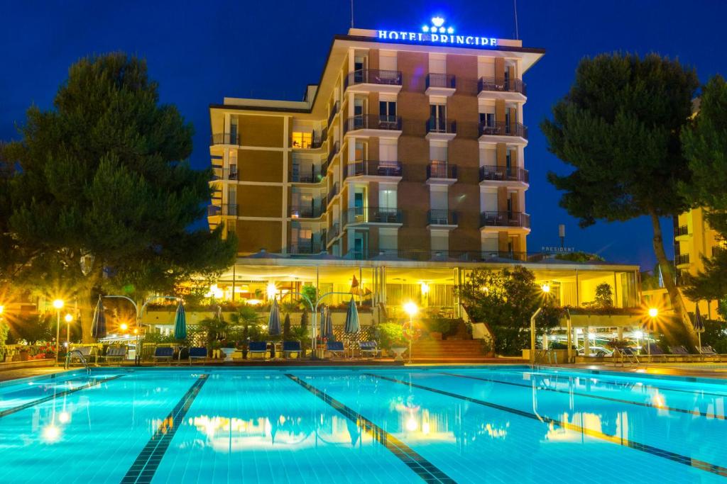 un hotel con piscina por la noche en Hotel Principe en Bibione