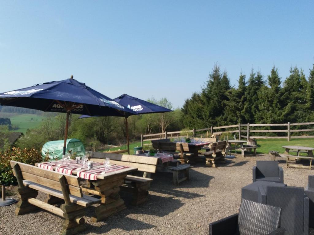 un grupo de mesas de picnic con sombrillas en Auberge "La Fourchette Paysanne" en Dochamps