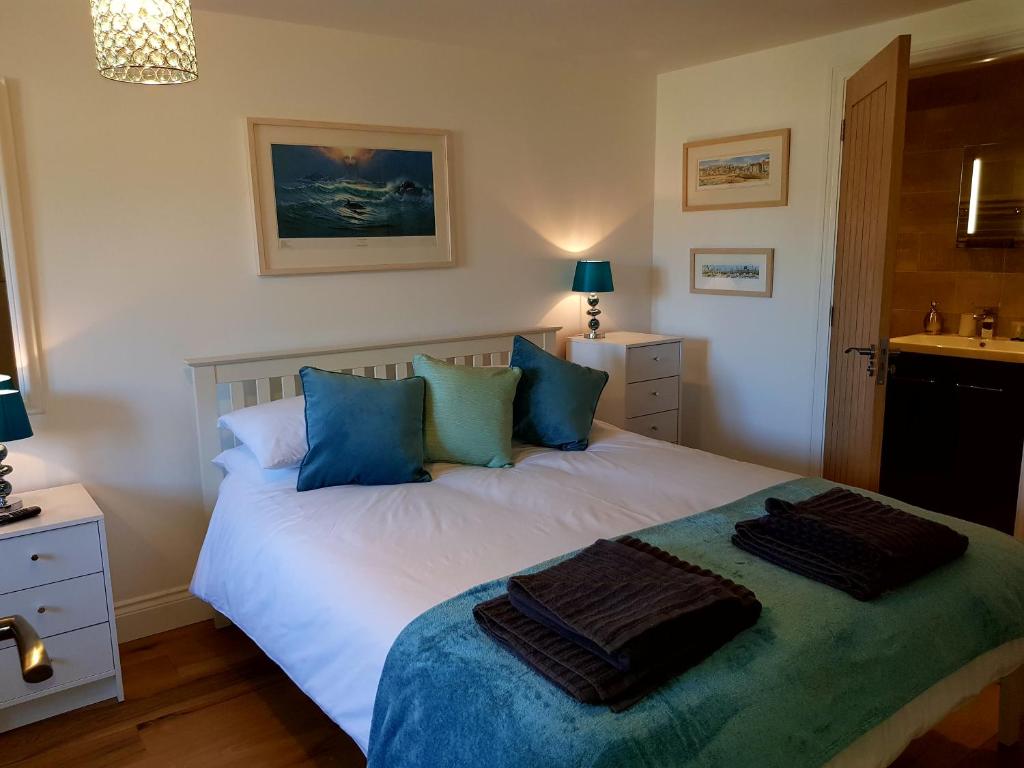 a bedroom with a white bed with blue pillows at Primrose House in St Ives