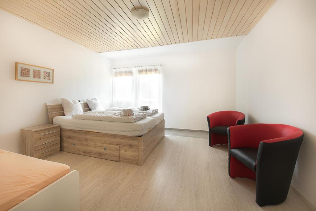 um quarto com uma cama, 2 cadeiras e uma janela em Mentenwirt Pension&Appartements em Sankt Martin