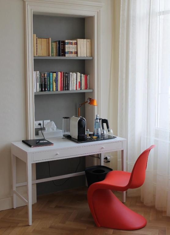 a desk with a red chair next to a book shelf at Villa Élyane in Colmar