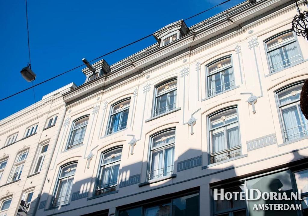 ein weißes Gebäude mit Fenstern auf einer Straße in der Unterkunft Hotel Doria in Amsterdam