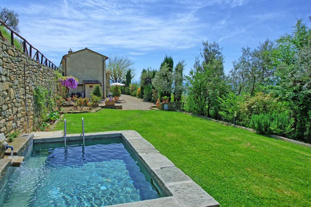 a backyard with a swimming pool in the grass at Villa Calcinaio by PosarelliVillas in Cortona