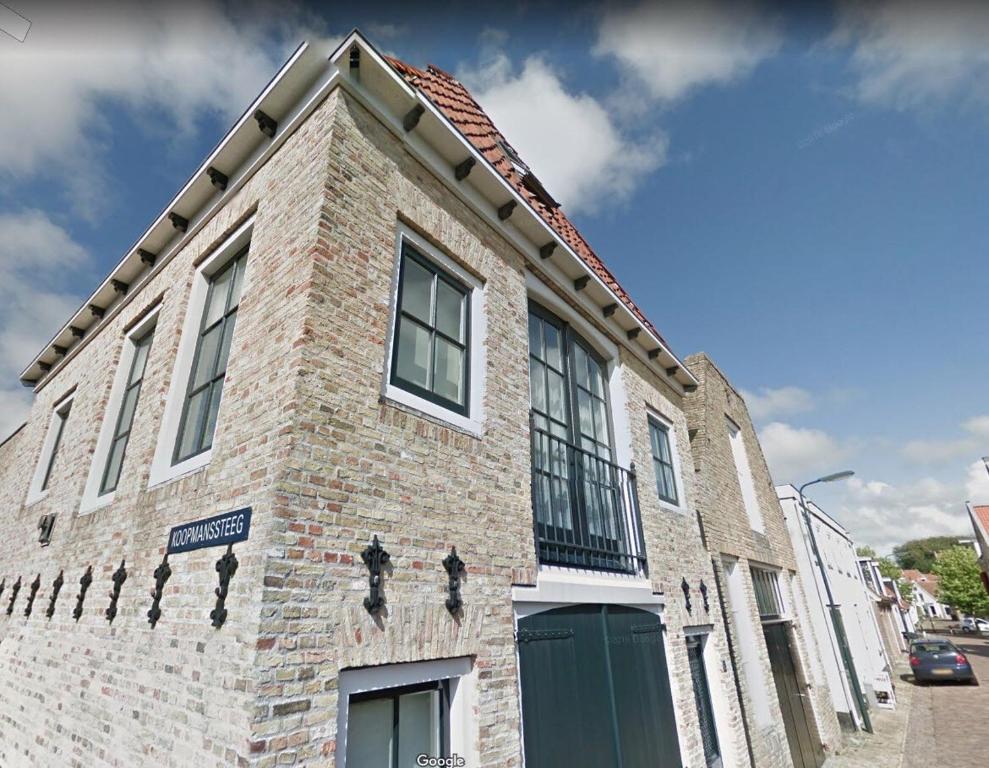 a brick building with a green door on a street at Ons Pakhuisje Harlingen in Harlingen