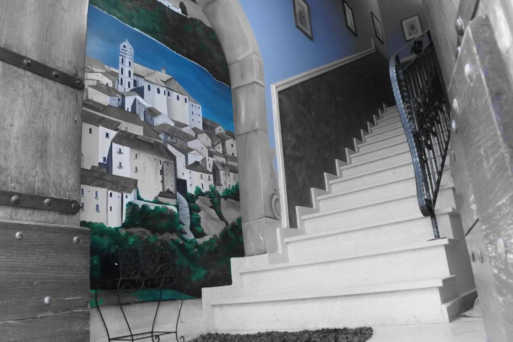une fresque murale sur le côté d'un bâtiment avec des escaliers dans l'établissement Affittacamere"Il Portale", à Spinoso