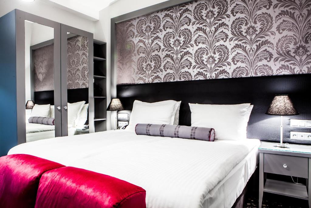 a bedroom with a large white bed with a red bench at Hotel Central Sarajevo in Sarajevo