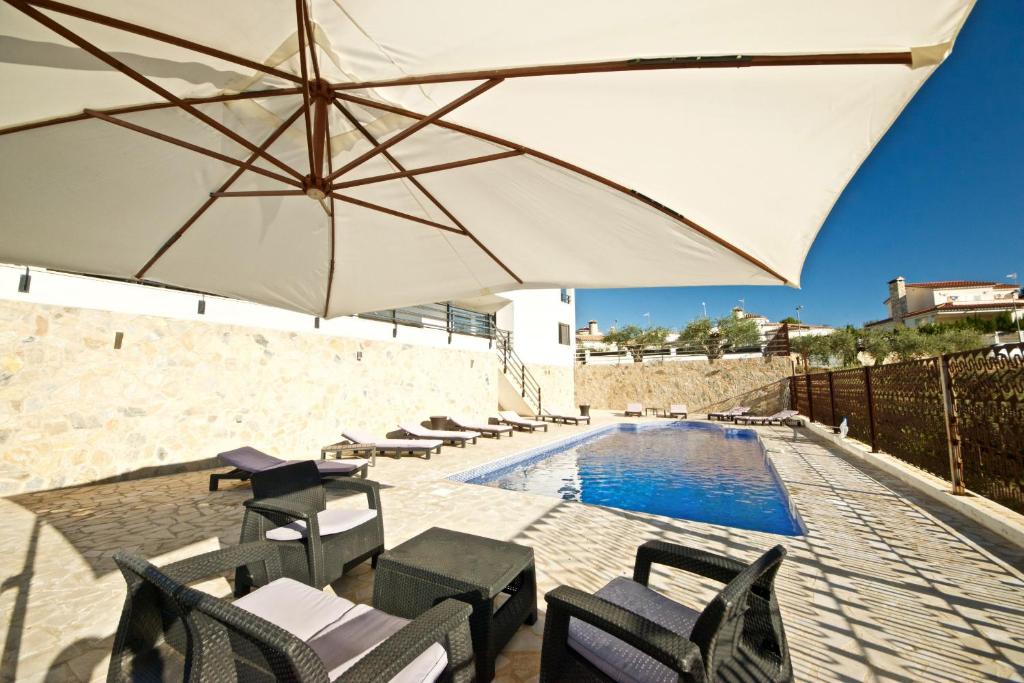 a patio with chairs and an umbrella and a pool at Parabellum in L'Ampolla