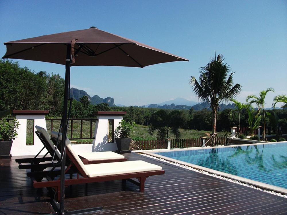 a table with an umbrella next to a swimming pool at Leelawadee Garden Resort in Ao Nam Mao