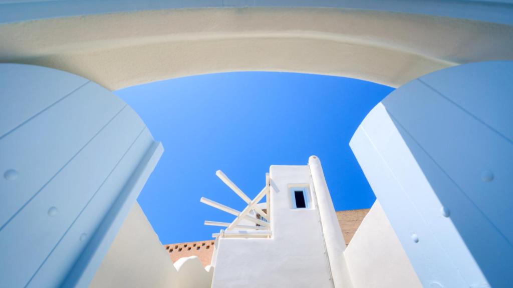 a view of a white building with a windmill at Christina's Cave House in Fira