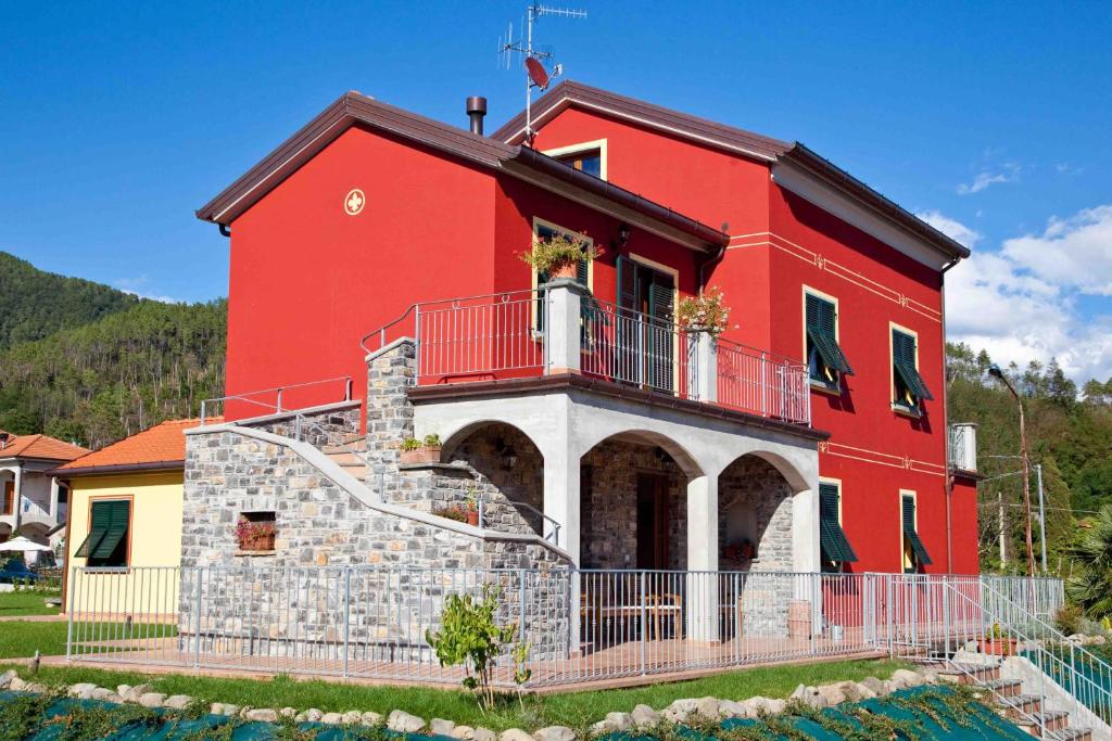 a red house with a balcony on top of it at Il Vecchio Noce in Brugnato
