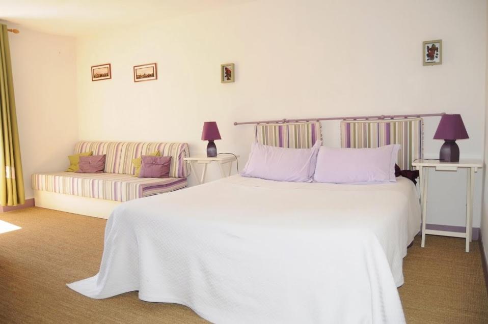 een witte slaapkamer met een wit bed en een bank bij LES RIVES DE L'ISLE in Saint-Astier