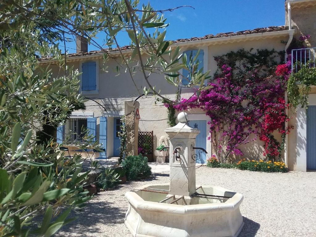 una fuente de piedra frente a una casa con flores en Mas des Bougainvillees, en Sernhac