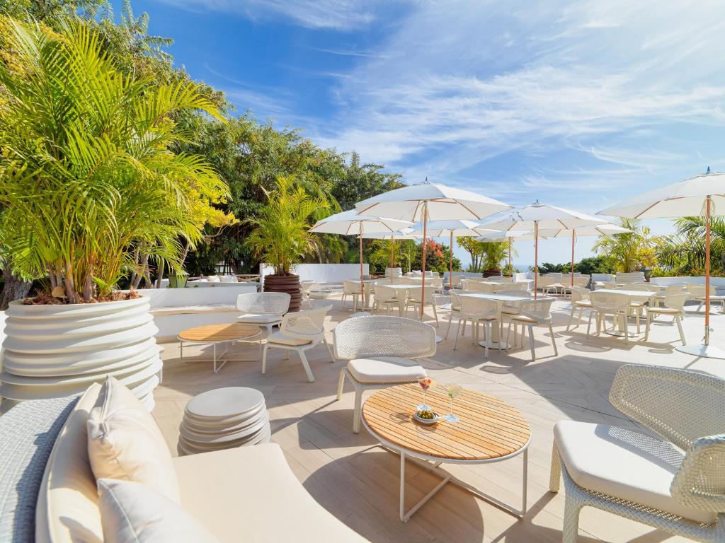 a patio with tables and chairs and umbrellas at Hotel Jardín Tecina in Playa de Santiago