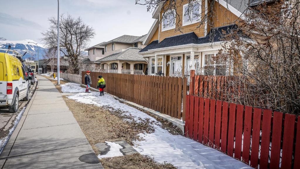 a woman walking down a sidewalk in front of a house at Valencia Suite - 2 Bedroom basement in Jasper