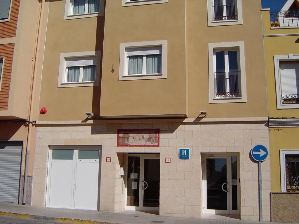 un edificio con dos puertas blancas de garaje en una calle en Hostal El Estudio en Almansa