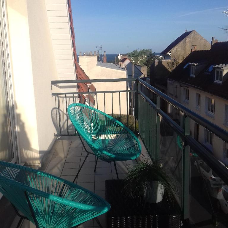 duas cadeiras verdes sentadas na varanda de um edifício em Balcon avec vue panoramique de la mer, le village et la campagne - parking privé em Wimereux