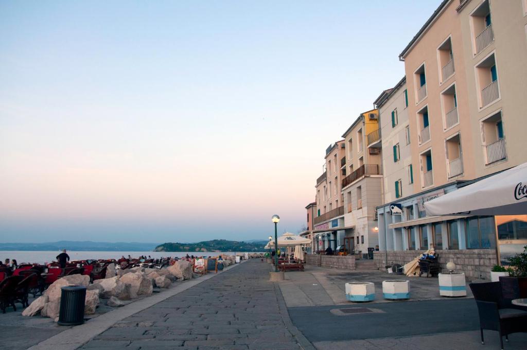 a group of people sitting on a sidewalk near the water at Spacious balcony apartment Piran in Piran