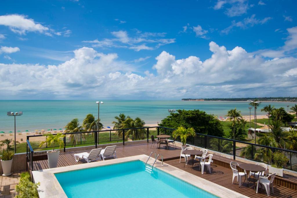 a view from the balcony of a resort with a swimming pool and the beach at Xênius Hotel in João Pessoa