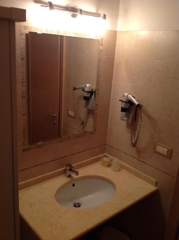 a bathroom with a sink with a mirror and a phone at Hotel Corallo in Torre Santa Sabina