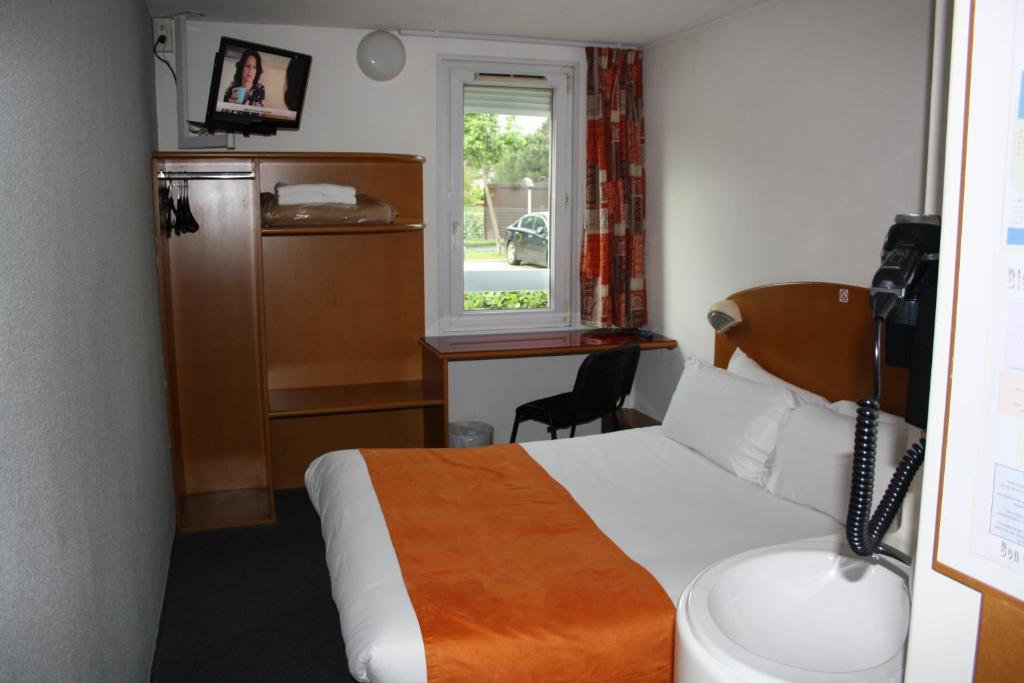 Cette chambre comprend un lit, un bureau et une fenêtre. dans l'établissement Hôtel Quick Palace Valence Nord, à Bourg-lès-Valence
