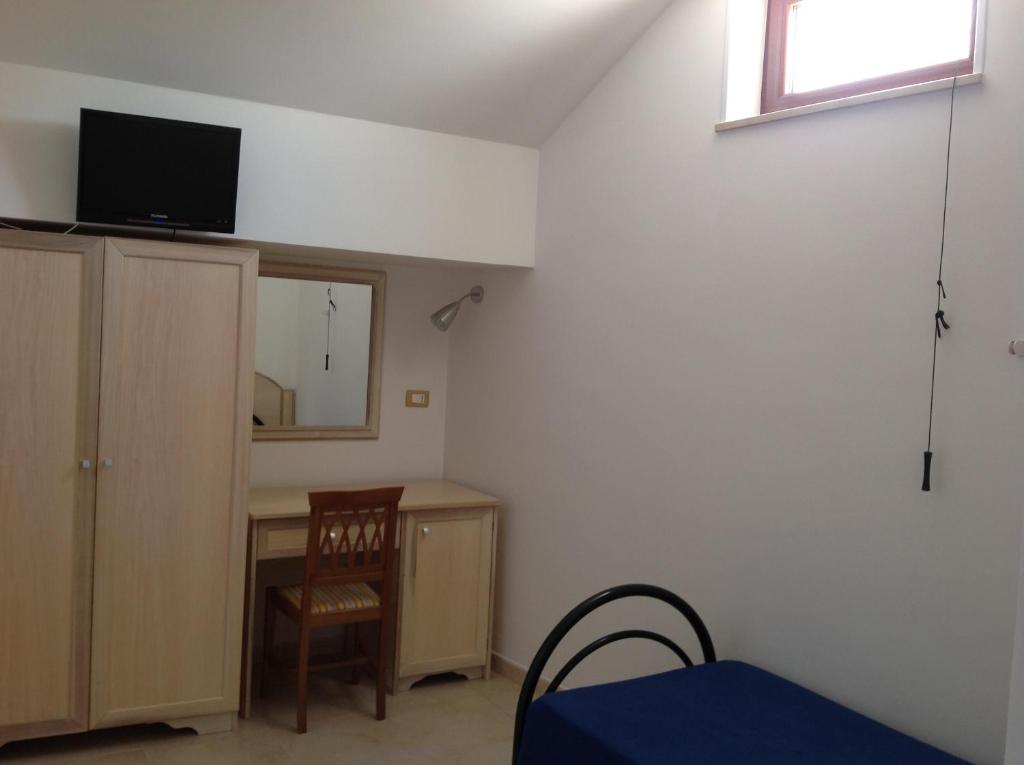 a room with a bed and a desk and a television at Hotel Corallo in Torre Santa Sabina