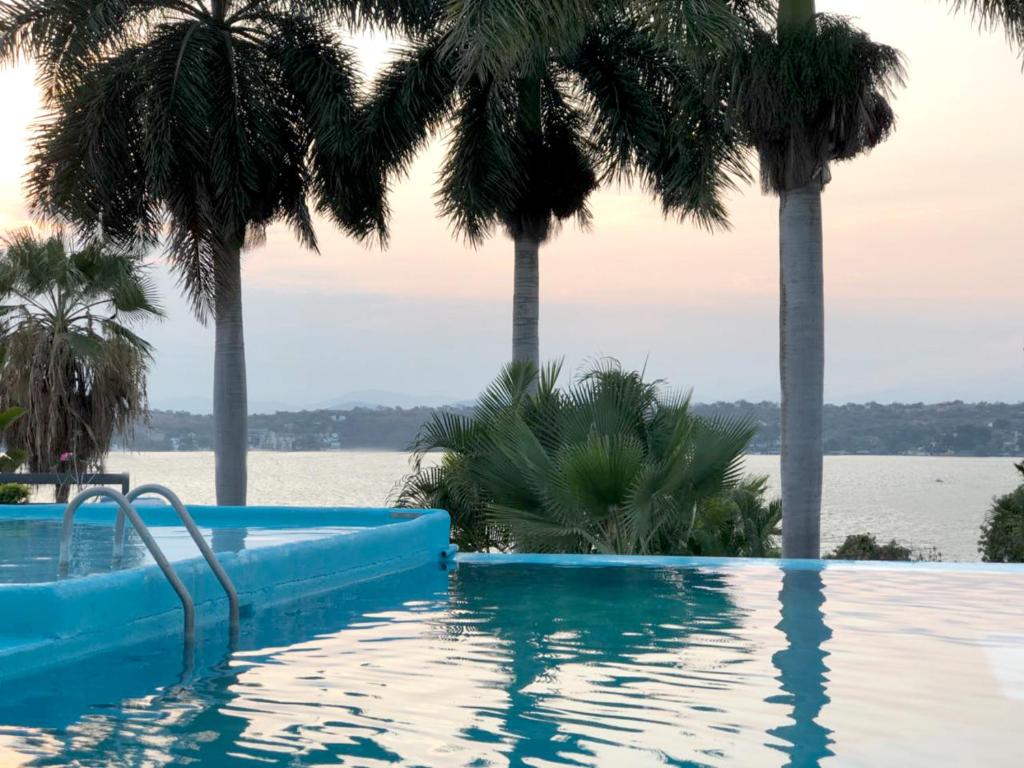 een zwembad met palmbomen en het water bij Hotel Infinity in Tequesquitengo