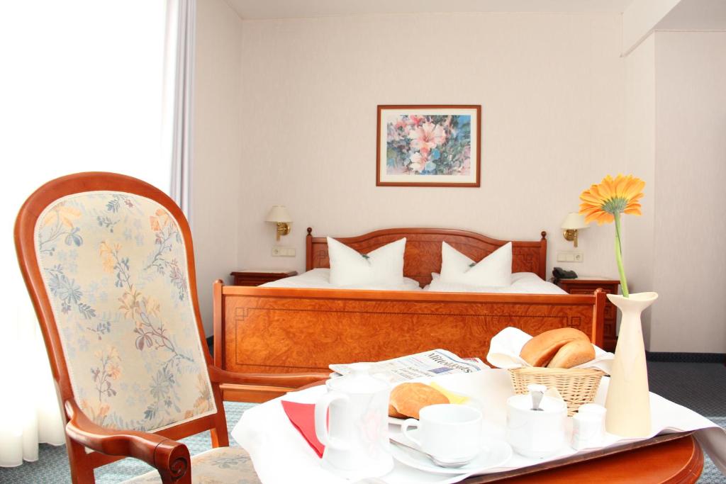 Un dormitorio con una cama y una mesa con comida. en Hotel Ascania, en Aschersleben