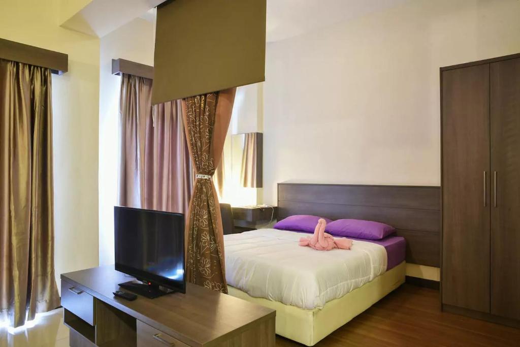 a bedroom with a bed and a desk with a television at Junikastay BLagoon Melaka in Malacca