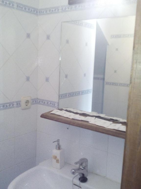 La salle de bains blanche est pourvue d'un lavabo et d'un miroir. dans l'établissement Apartamento Rural El Oso 2, à Pola de Somiedo