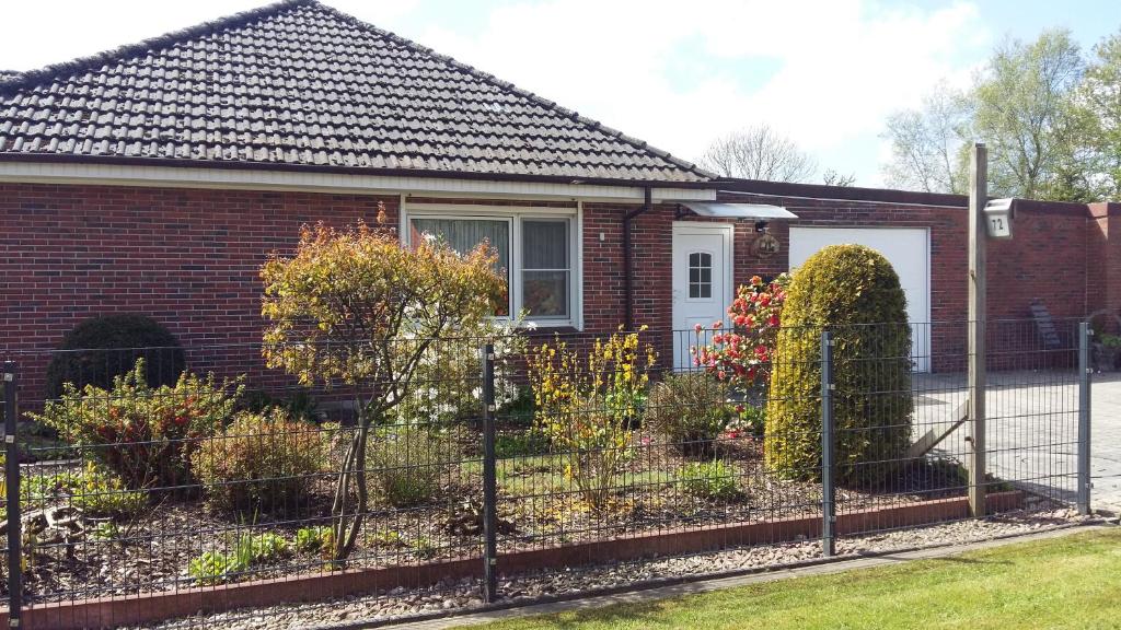a brick house with a fence in front of it at Ferienwohnung Haus Antje in Norden