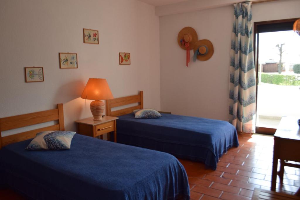 Una habitación de hotel con dos camas y una ventana. en Apartamento T2 com Piscina e Wifi a 350 metros da Praia, en Roja- Pé