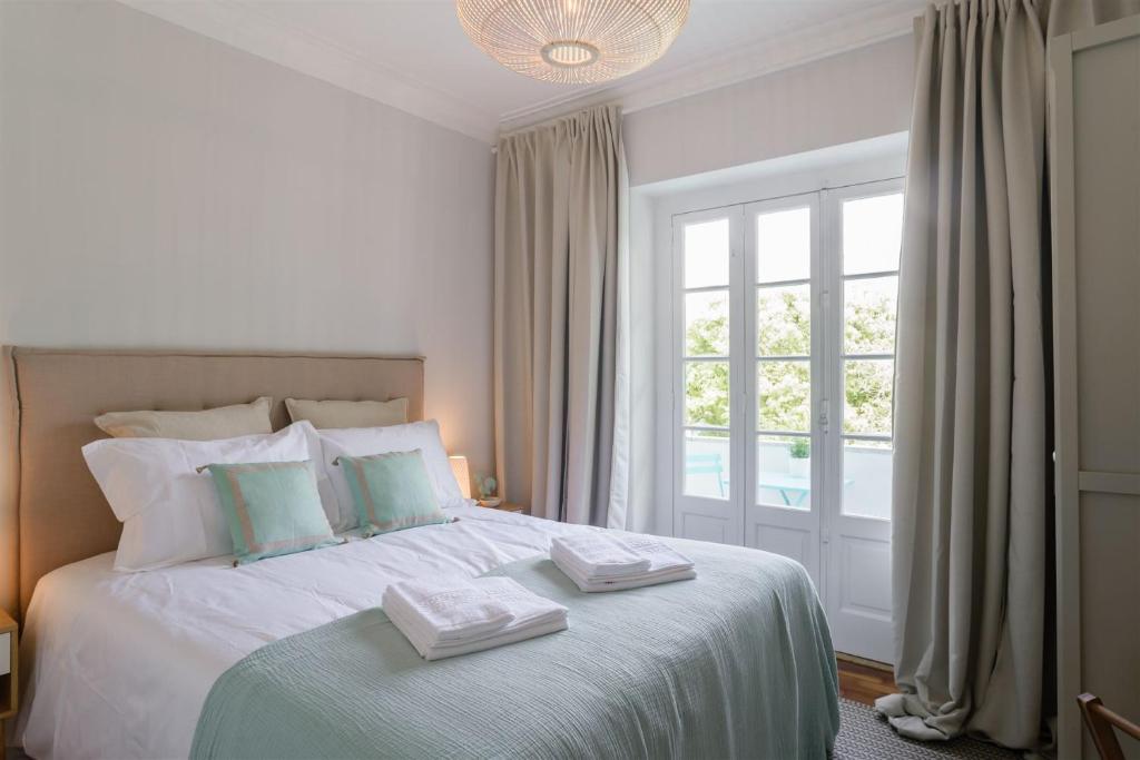 een slaapkamer met een wit bed en 2 handdoeken bij Pedrouços 37 in Lissabon