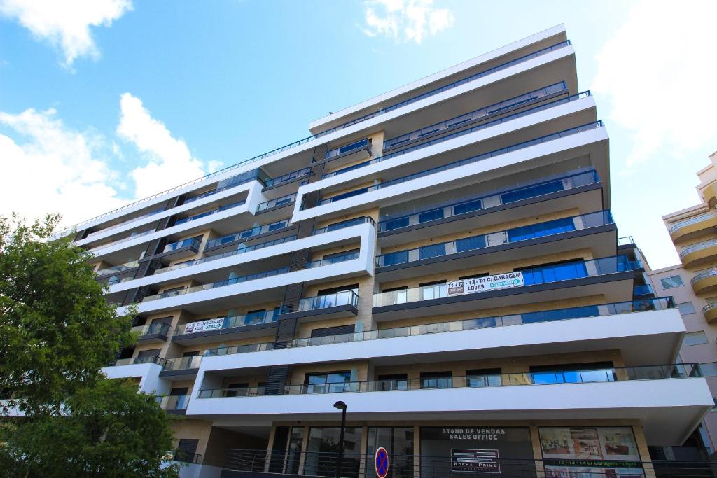 ポルティマンにあるRocha Prime IMO88の青い窓が備わる白い高層アパートメントです。