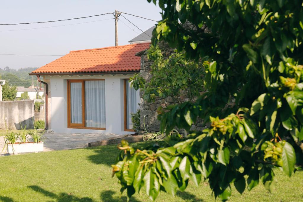 una casa blanca con techo naranja en Galpon Boutique Aldea De Abaixo en Palas de Rei 