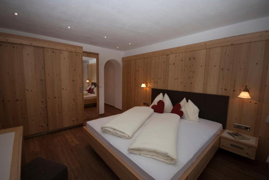 Schlafzimmer mit einem großen weißen Bett und Holzwänden in der Unterkunft Landhaus Summerer in Sexten